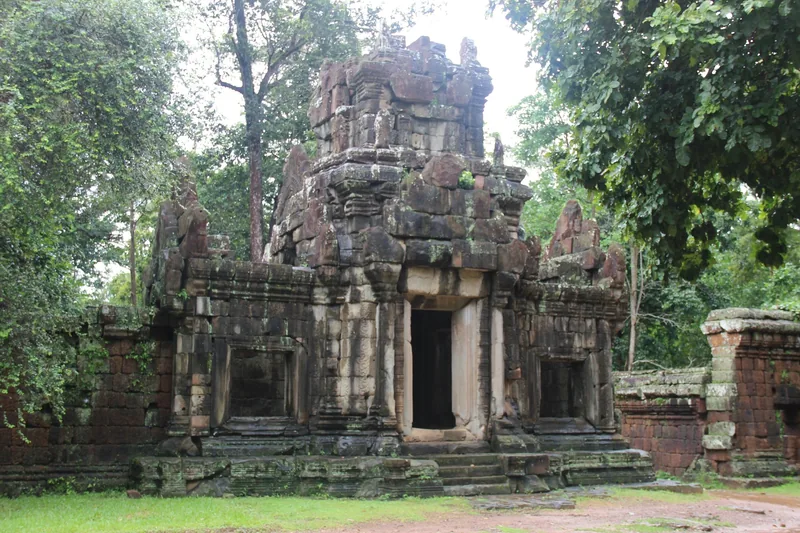 A weathered stone tower with a central doorway stands amid greenery at Angkor Thom near Siem Reap.