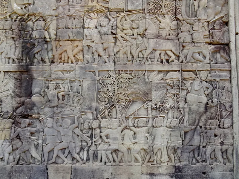 Ancient stone bas-relief carvings depicting warriors and battle scenes at Angkor Thom's Bayon temple in Siem Reap.