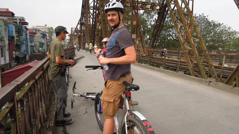 A cyclist wearing a helmet pauses on the steel truss of Long Bien Bridge in Hanoi.