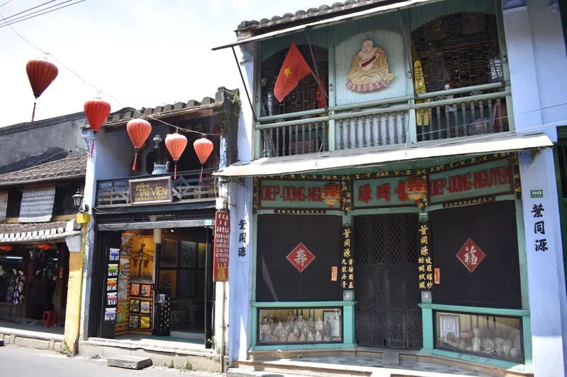 Red lanterns and Vietnamese signboards decorate old shophouses along a street in Hoi An.