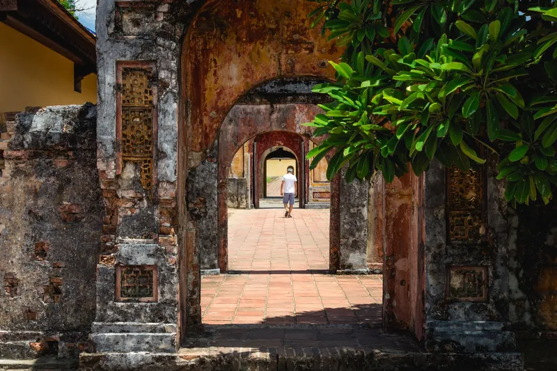 A visitor walks through a series of weathered stone archways inside Hue's ancient citadel complex.
