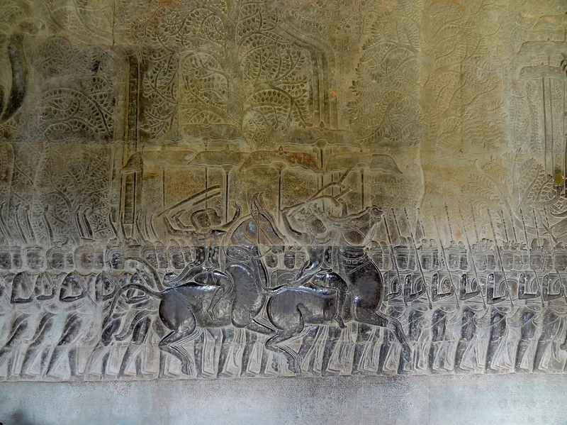 Ancient bas-relief carvings of soldiers and horsemen marching in procession on a stone wall at Angkor Wat, Siem Reap.