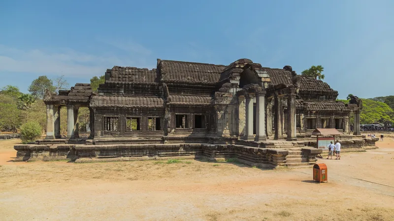 A weathered stone library building with columned porches stands beside Angkor Wat in Siem Reap.
