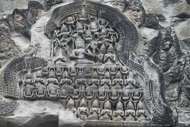 Intricate stone carving of deities and worshippers on a temple wall at Angkor, Siem Reap.