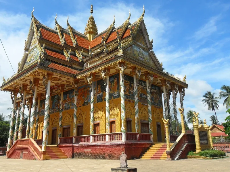 Ornate golden Khmer temple with tiered roofs and painted columns at Wat Kor in Battambang.