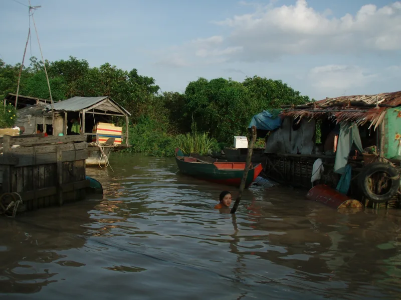 A child swims between floating houses and boats on a river in Siem Reap, Cambodia.