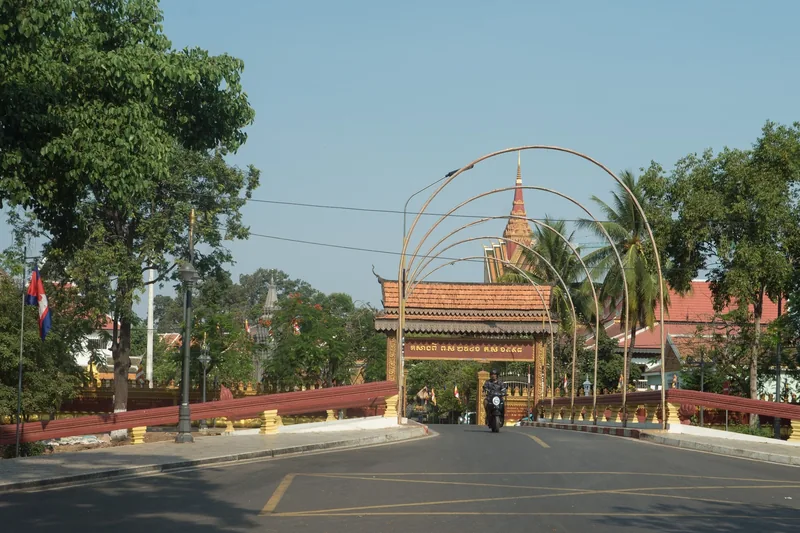 A decorated bridge with arched frames leads to Wat Preah Prom Rath temple in Siem Reap.