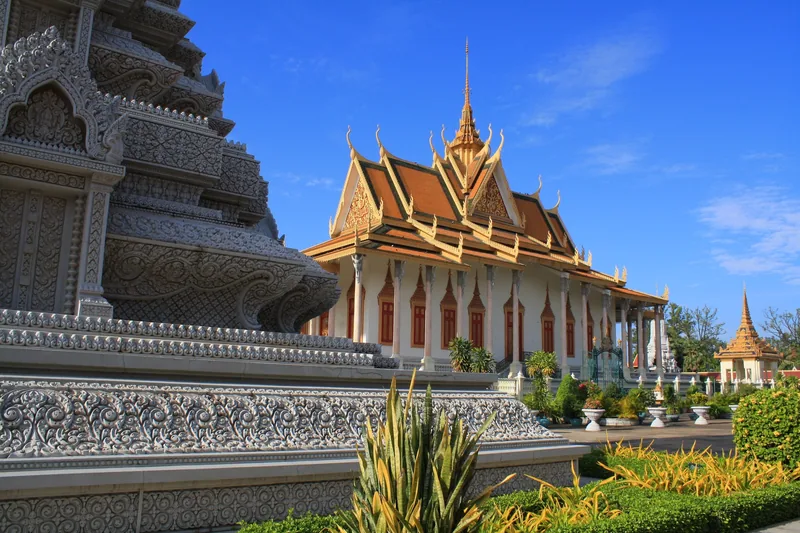 Ornate stupa and multi-tiered roofs of the Silver Pagoda temple complex under a clear blue sky in Phnom Penh.