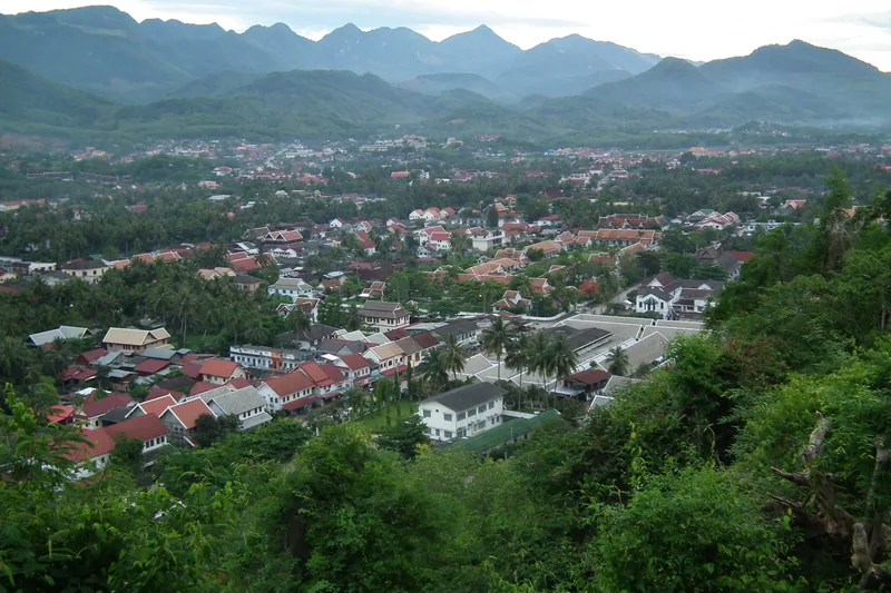 Elevated view of Luang Prabang's rooftops and temples surrounded by mountains and greenery