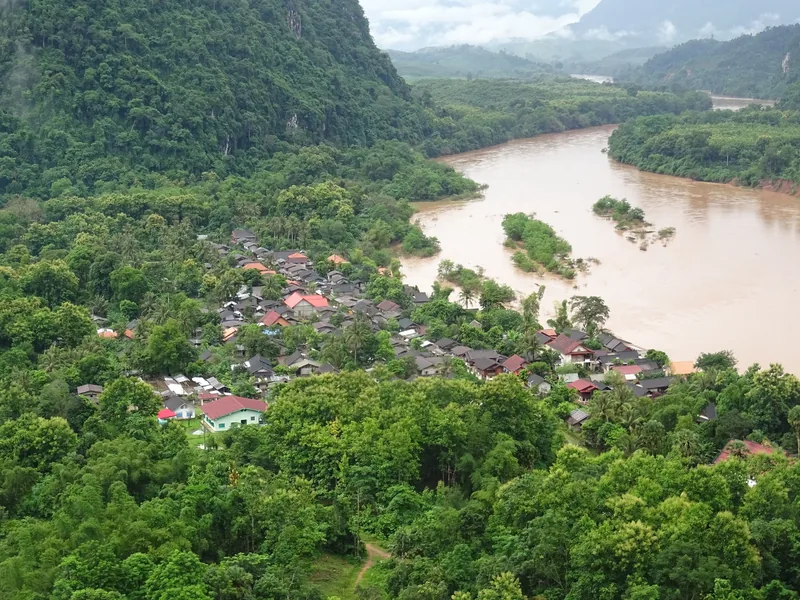 Aerial view of Nong Khiaw village nestled between limestone karsts and the muddy Nam Ou River in Laos.