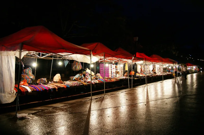 Red-roofed stalls line a wet street at the night market in Luang Prabang, Laos.
