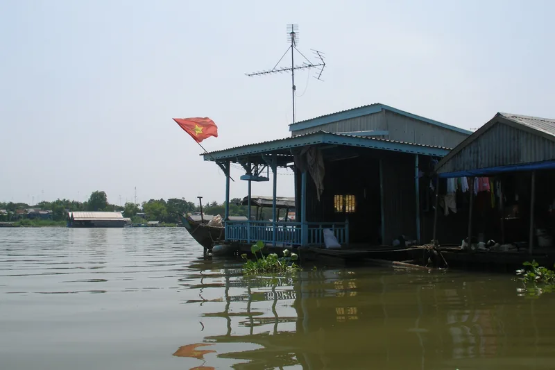 A floating house with a Vietnamese flag sits on the Bassac River in Chau Doc, Mekong Delta.