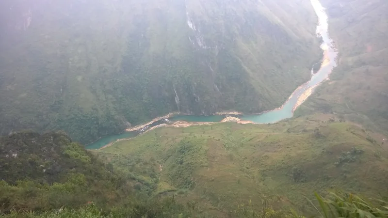 A turquoise river winds through the deep Nho Que canyon as seen from Ma Pi Leng Pass in Ha Giang.