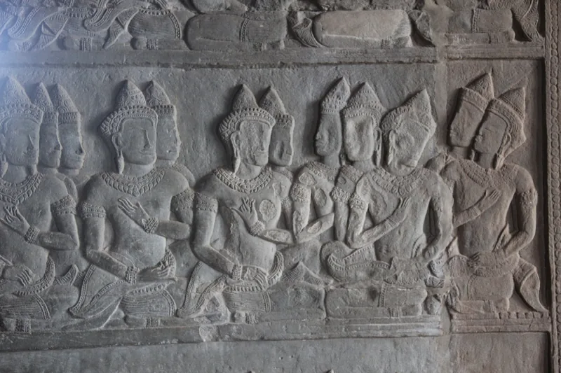 Ancient stone bas-relief carvings of crowned figures line a temple wall at Angkor Wat in Siem Reap.