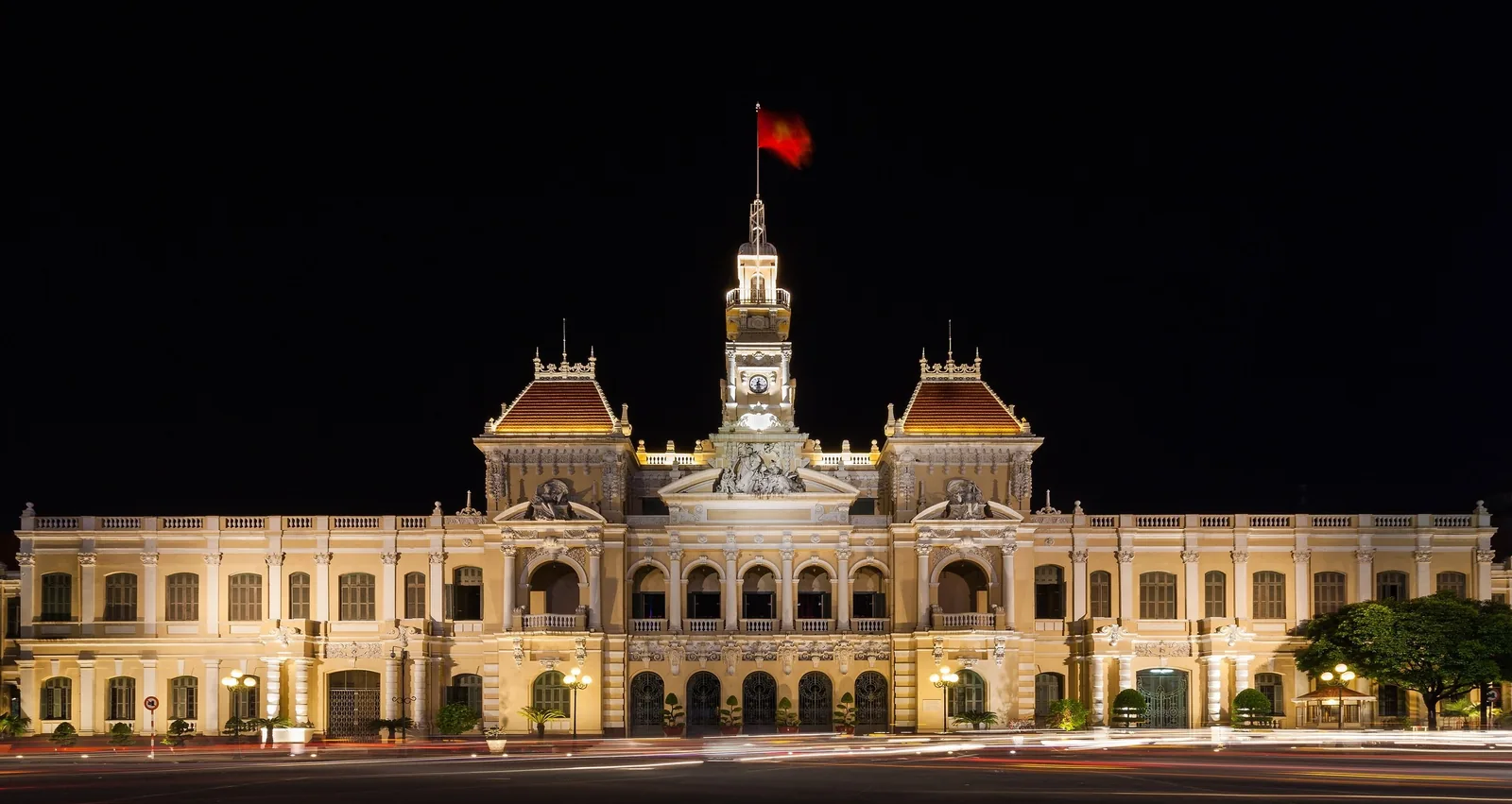 Ho Chi Minh City Hall glows at night with its French colonial facade and flag-topped clock tower.